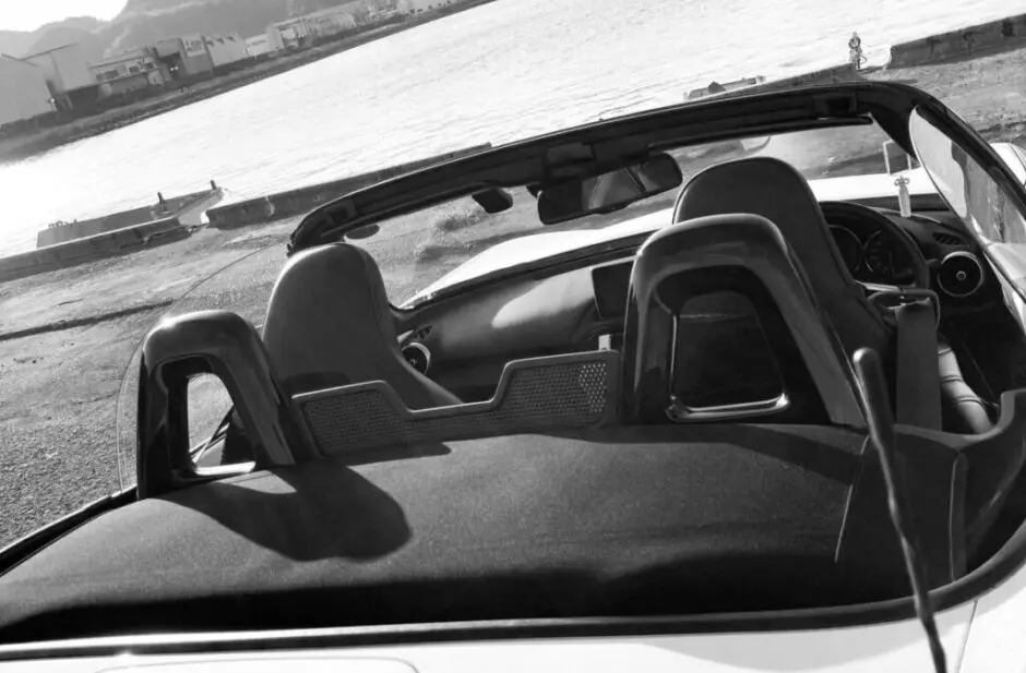 オープンにしたロードスターの後席越しに海辺を望む風景。手放したあとも心に残る満足感を表す写真