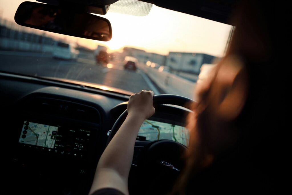 夕暮れの高速道路を運転する女性の後ろ姿
