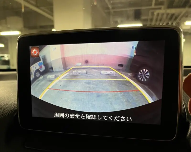 薄暗い駐車場でバックモニターに駐車枠のガイド線が表示されている様子