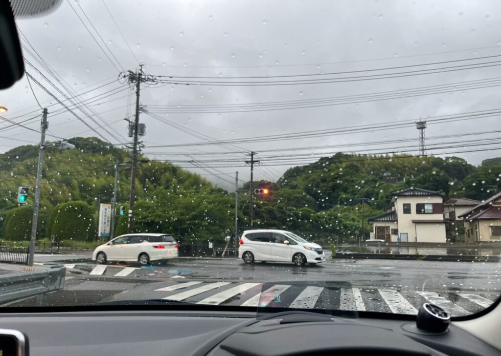 雨の日にフロントガラス越しに見た道路の風景