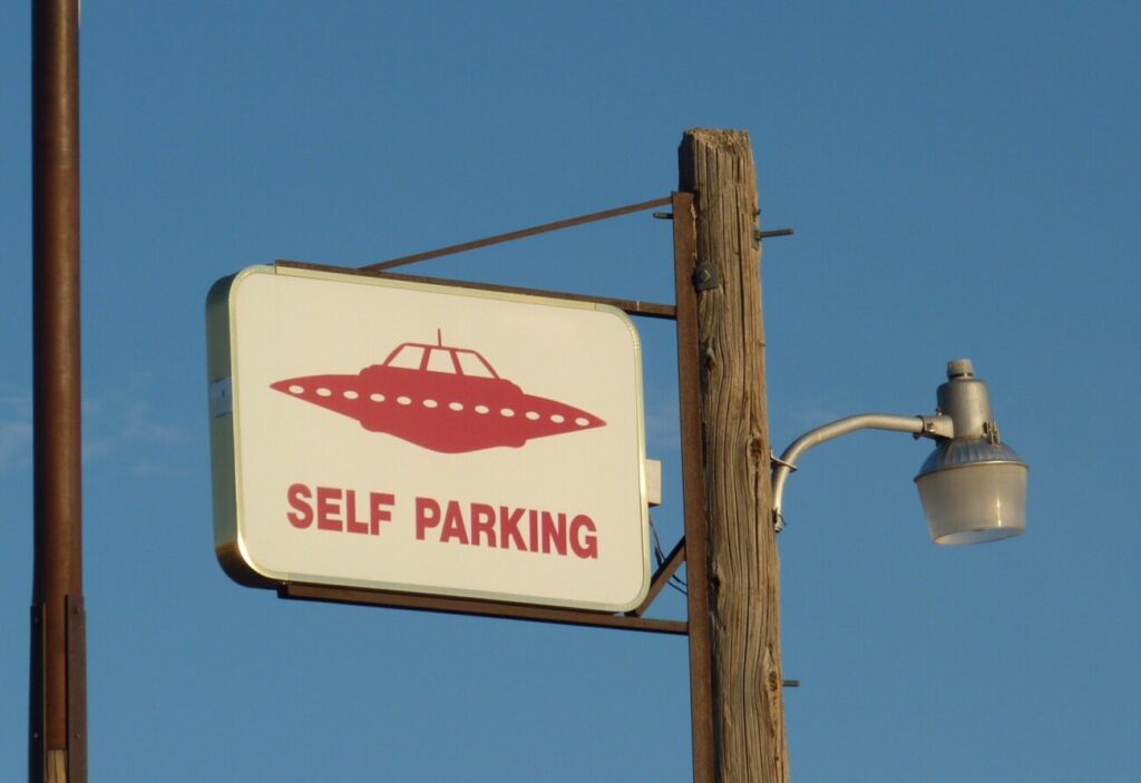 青空の下、電柱に取り付けられた「SELF PARKING」と書かれた看板