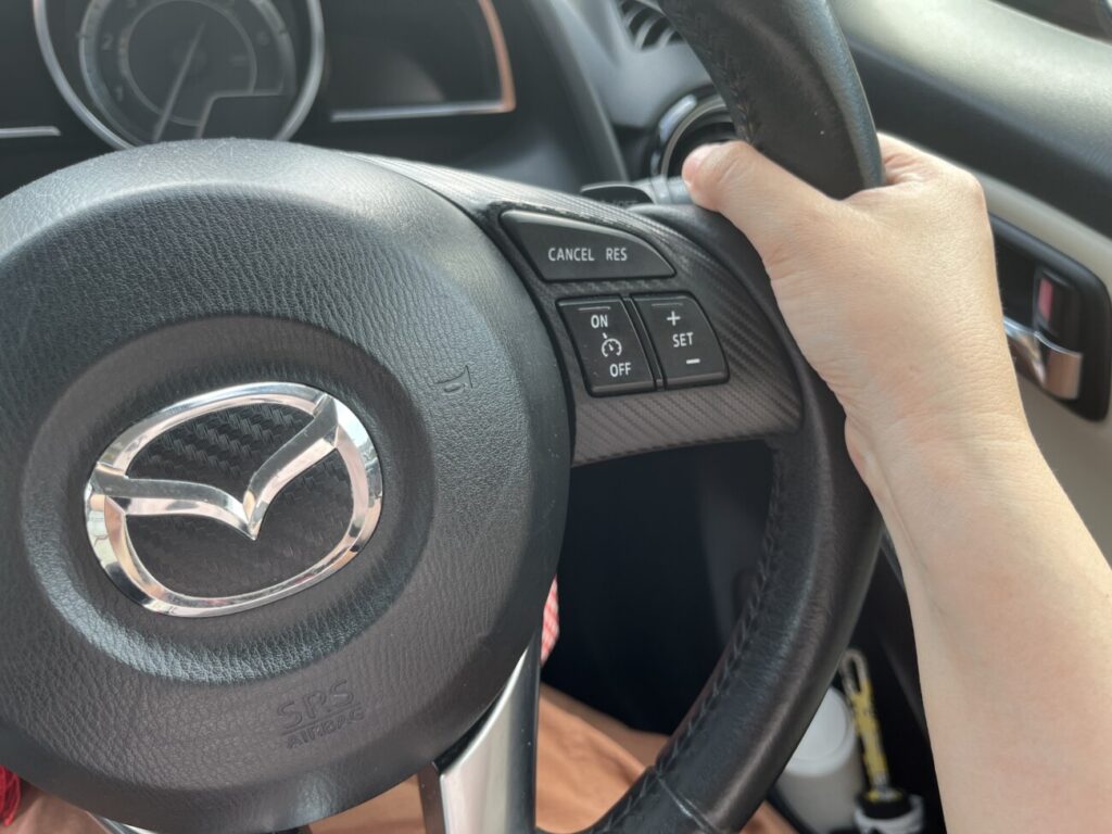 車のハンドルを握って運転する手元
