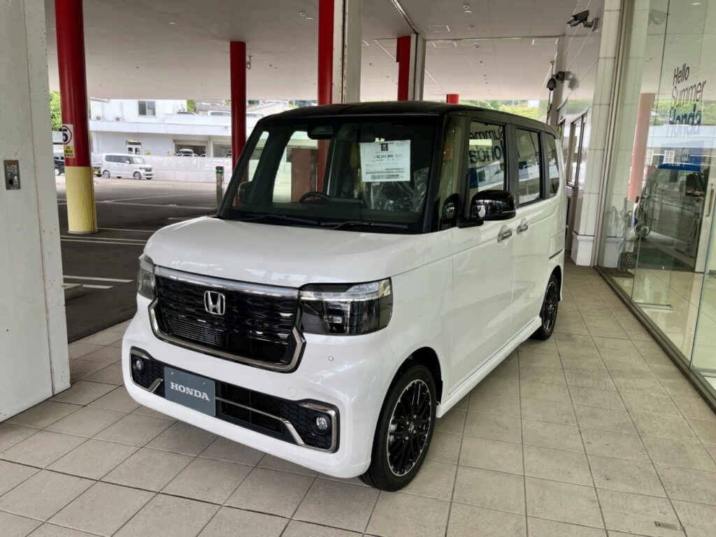 販売店の店先に置かれた白い軽自動車。運転しやすさと好みの両方を大切にして一台を選ぶ