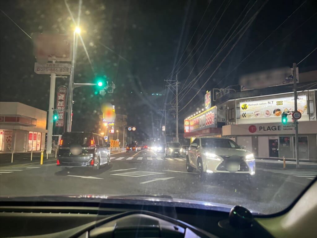 夜の交差点で対向車を確認しながら待つ車内