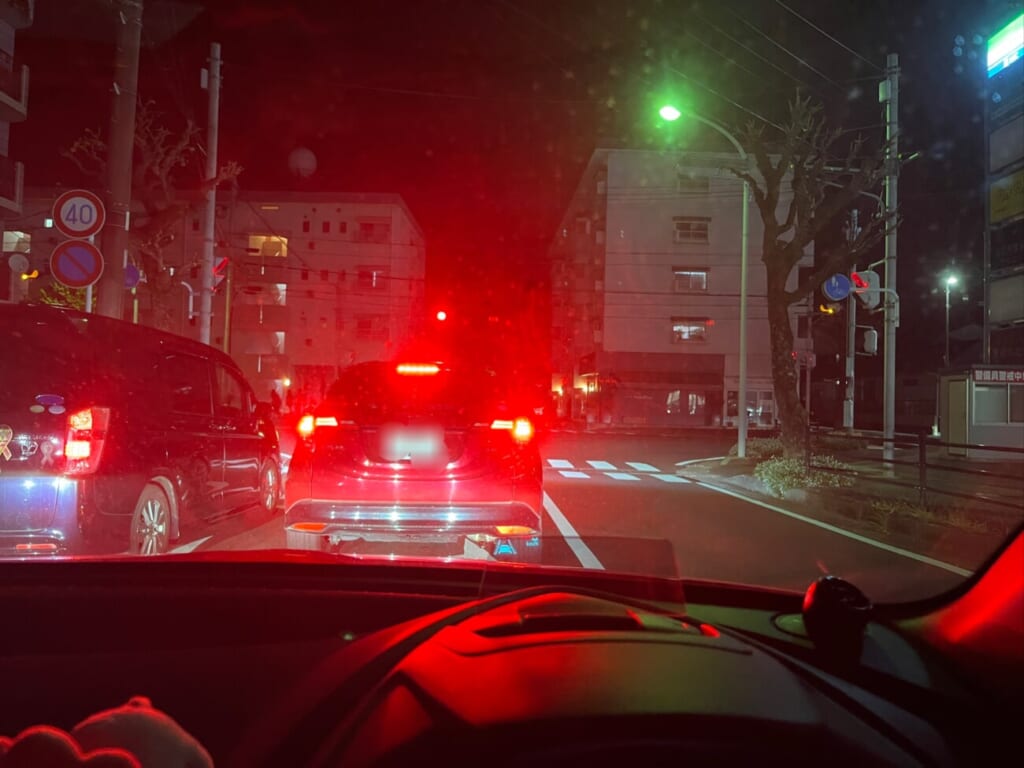 夜の道路で前方の車列と信号を確認する車内